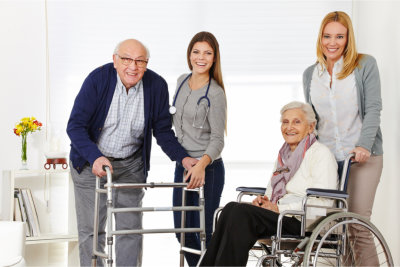 caregivers and elderly couple smiling