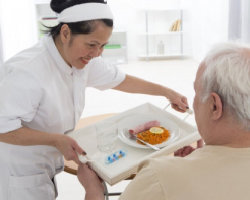 caregiver serving food to an elderly man